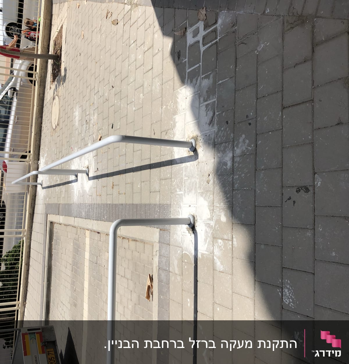 מעקה מתכת לבן על מדרכה מרוצפת